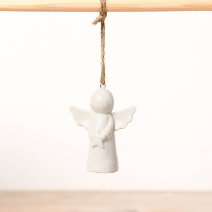 White ceramic angel ornament hanging on a wooden rod with twine against a white background