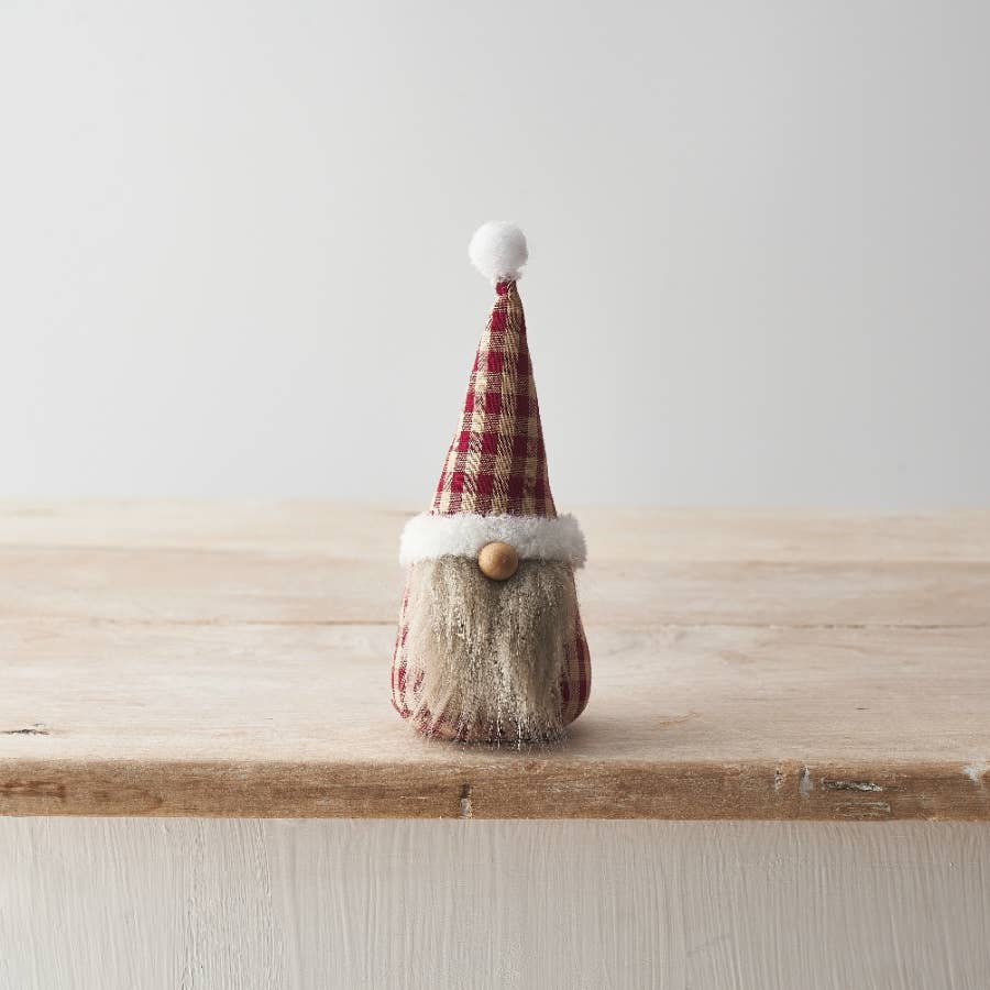 Small gnome figurine with a gingham hat on a wooden surface