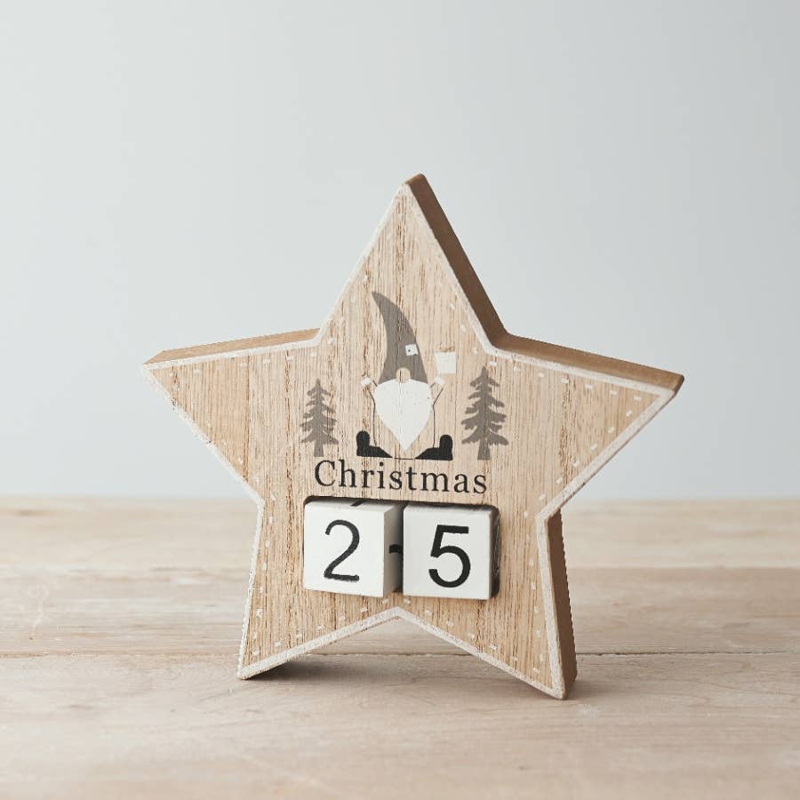 Wooden star-shaped Christmas countdown decoration with a gnome and trees design on a light background