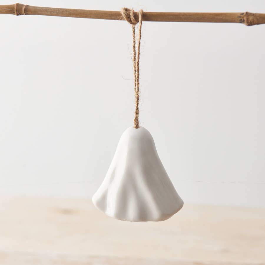 White ghost ornament hanging on a stick against a light background
