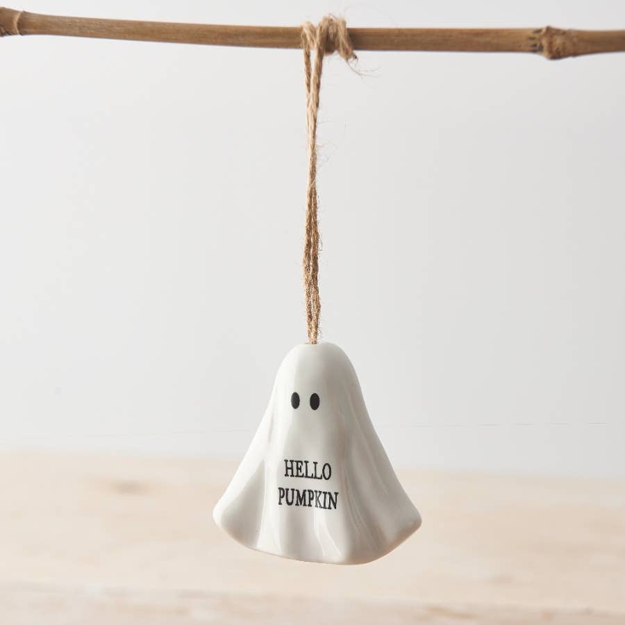 White ghost-shaped ornament with 'HELLO PUMPKIN' text hanging on a branch.