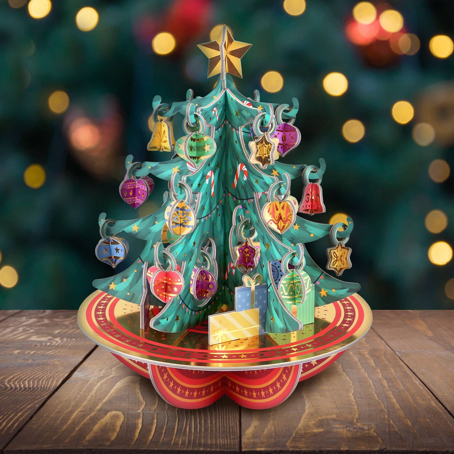 Decorative Christmas tree 3d pop-up advent calendar with colourful ornaments on a wooden surface with a blurred festive background.
