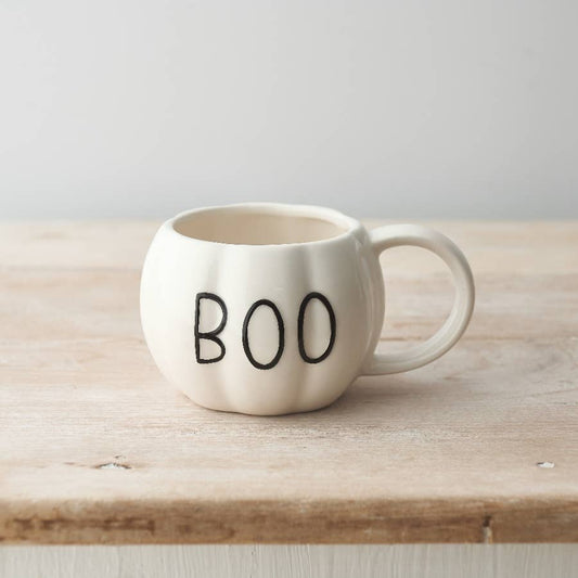 White mug with 'BOO' text on a wooden surface
