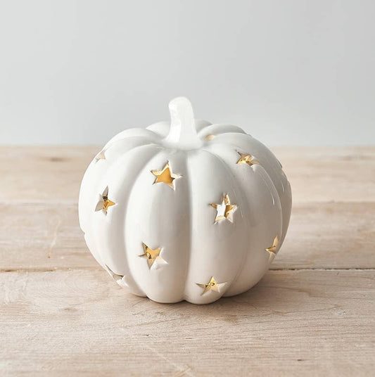 White ceramic pumpkin with star designs on a wooden surface