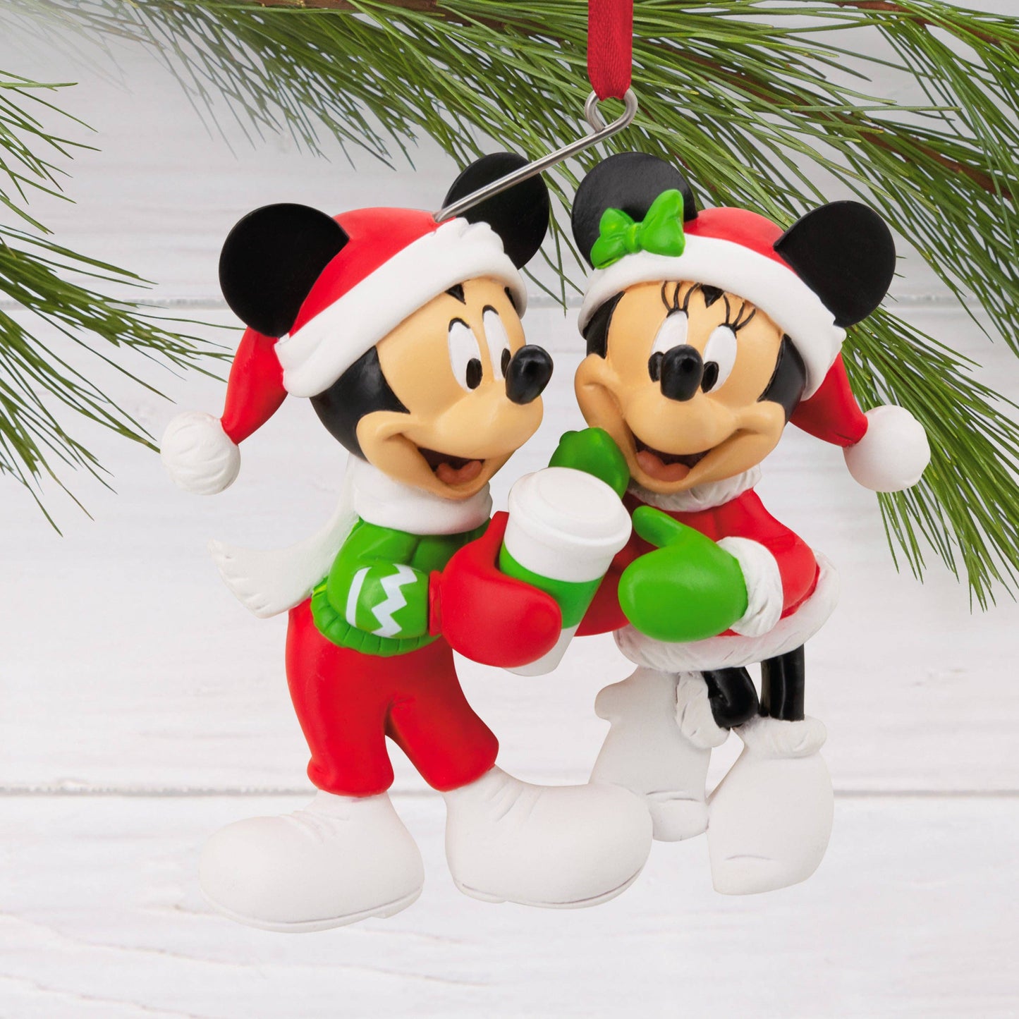Christmas-themed Mickey and Minnie Mouse ornament on a white background hanging from a Christmas tree.