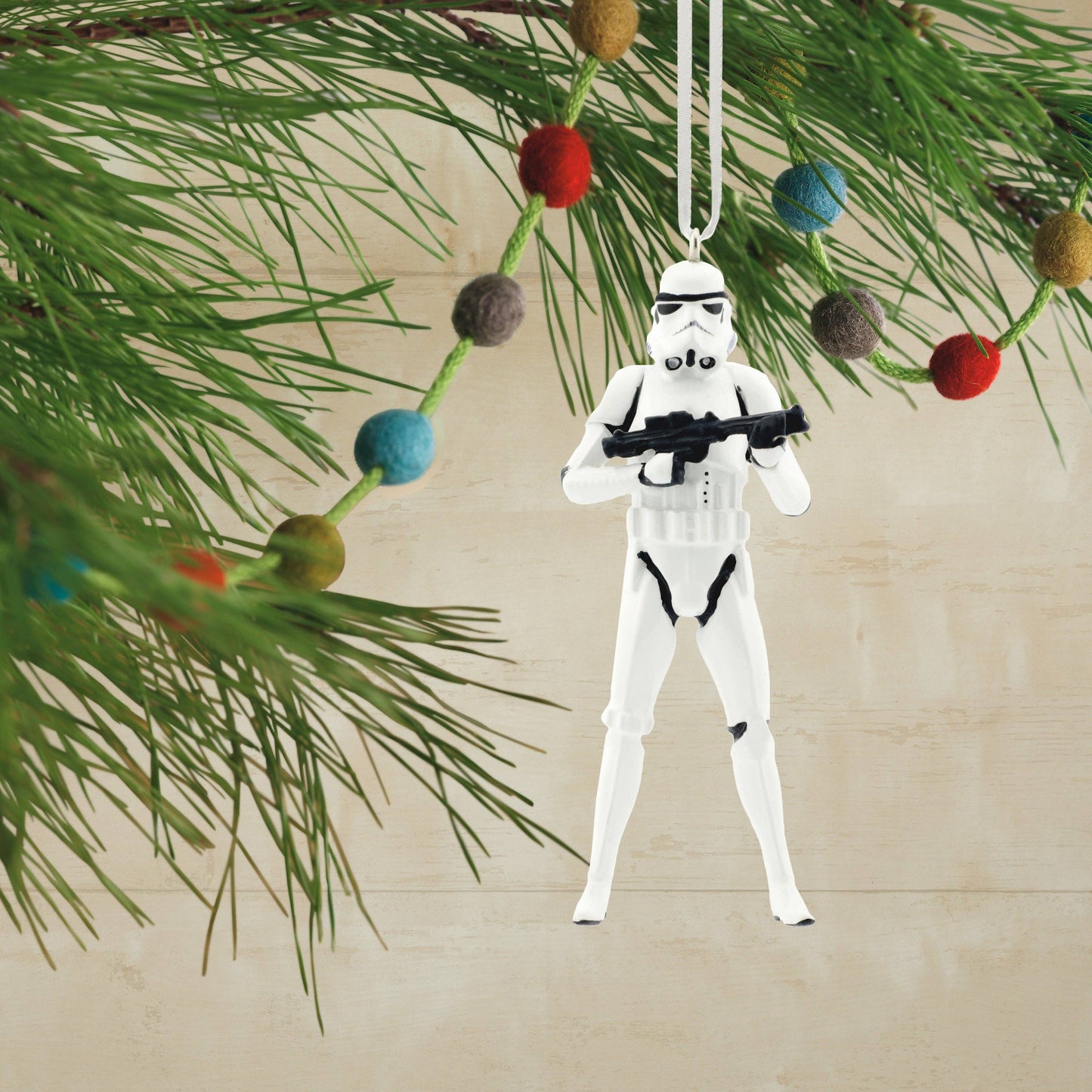Stormtrooper ornament hanging on a Christmas tree with colorful ornaments.