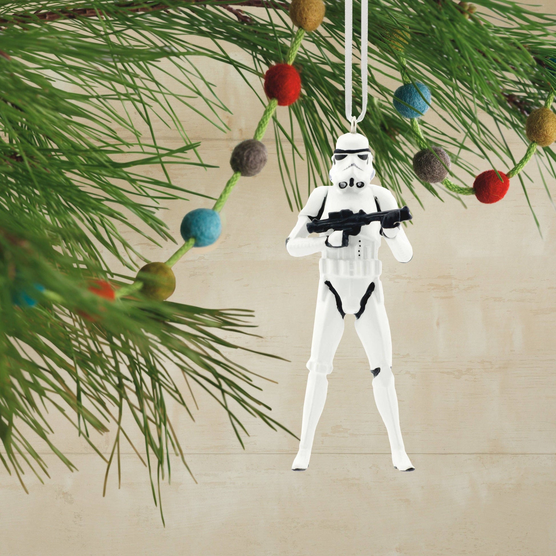 Stormtrooper ornament hanging on a Christmas tree with colorful ornaments.