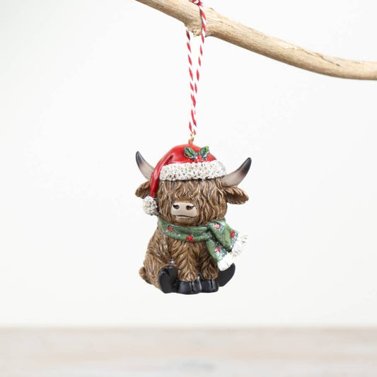 Highland cow ornament with a Santa hat and scarf on a white background