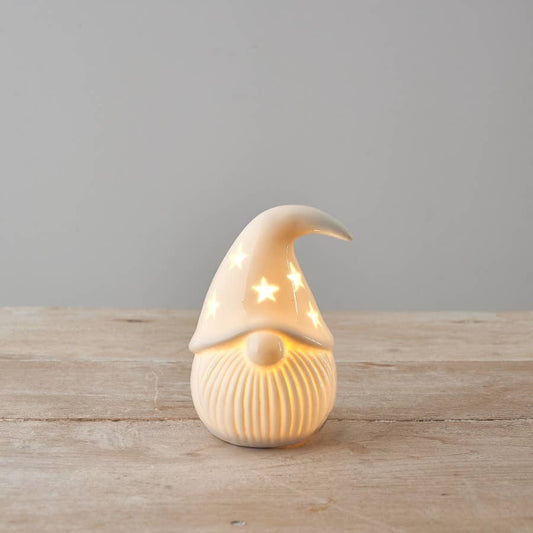 Ceramic gonk shaped light ornament on a wooden surface with a gray background