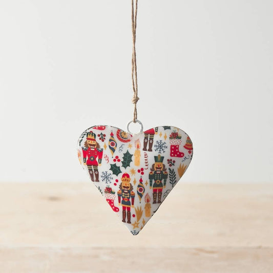 Heart-shaped Christmas ornament with nutcrackers and holly on a white background