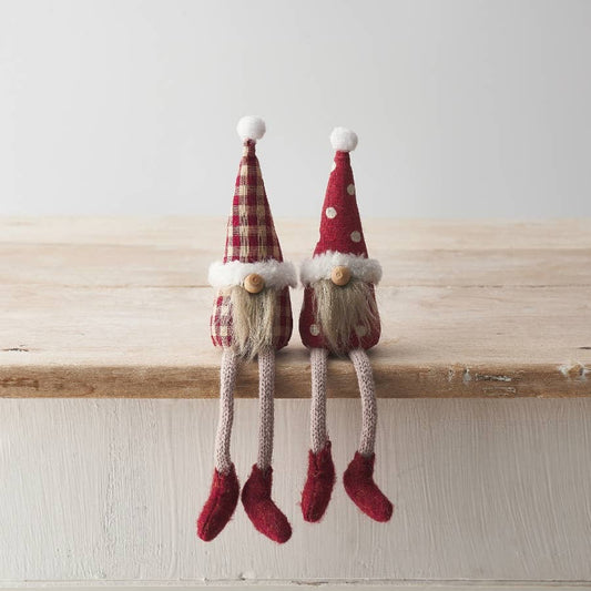 Two small decorative gnomes with red hats on a wooden surface.