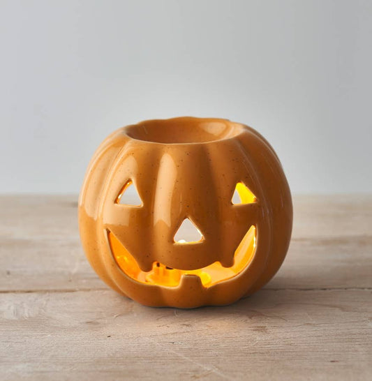 Ceramic jack-o'-lantern on a wooden surface with a neutral background