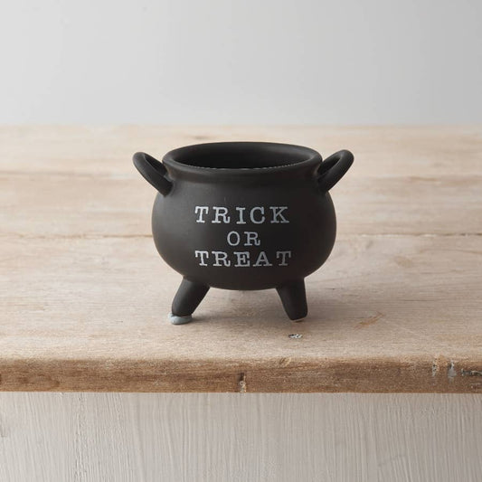 Black cauldron with 'TRICK OR TREAT' text on a wooden surface