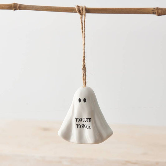 White ghost-shaped ornament with 'Too Cute To Spook' text hanging on a branch.