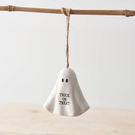 White ghost-shaped decoration with 'TRICK OR TREAT' text hanging on a branch.