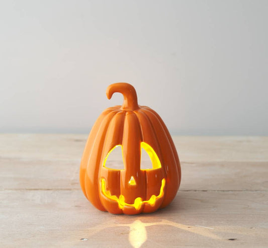 Ceramic pumpkin with a carved face on a wooden surface