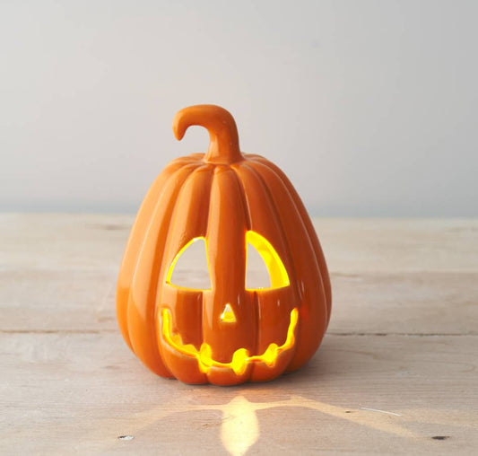 Ceramic pumpkin with a carved face on a wooden surface